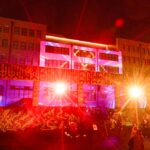 grafitti building illuminated at night by glowing orange and red spotlights