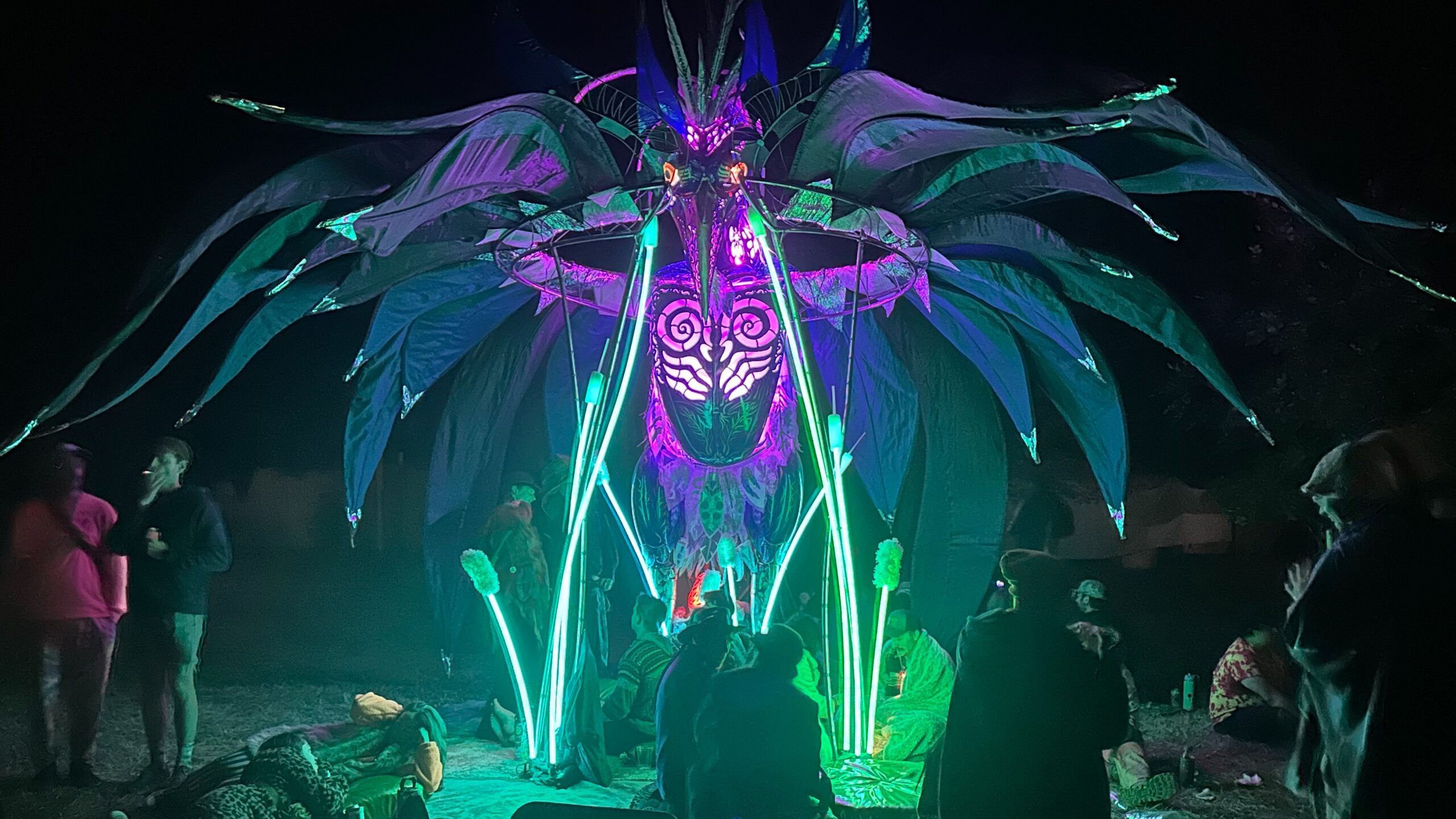 giant illuminated metal bird at outdoor art festival at night