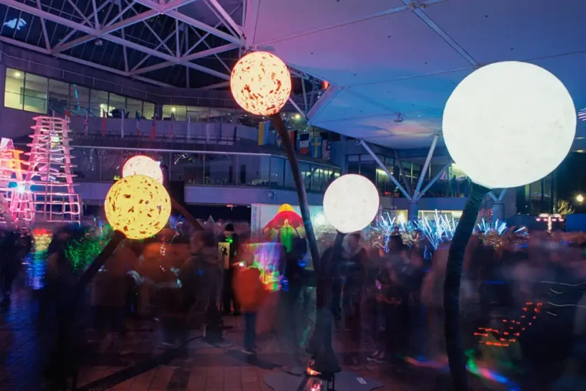 giant glowing orbs on arched poles during a light festival at night with giant crowd admiring