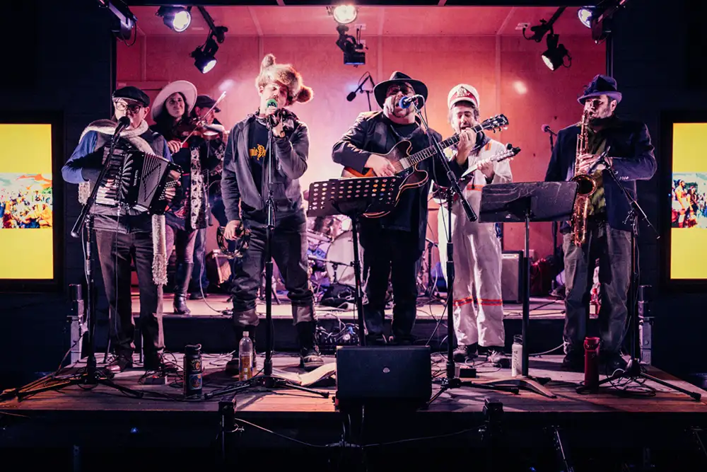 7 band members play music on an outdoor stage at night