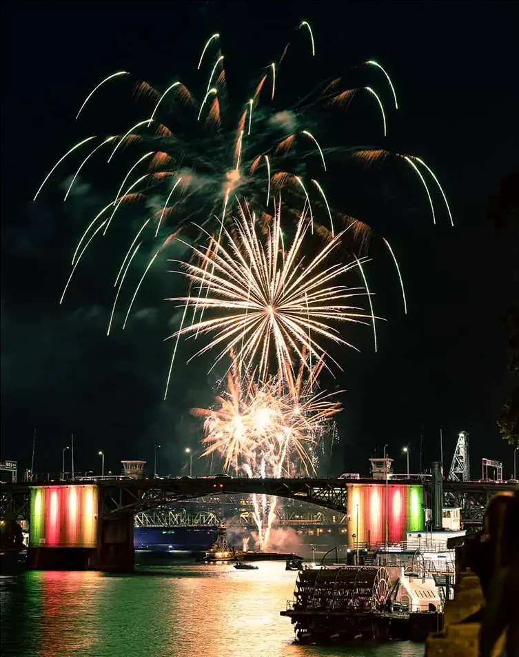 Downtown city bridge illuminated by colorful lights at night during fireworks display