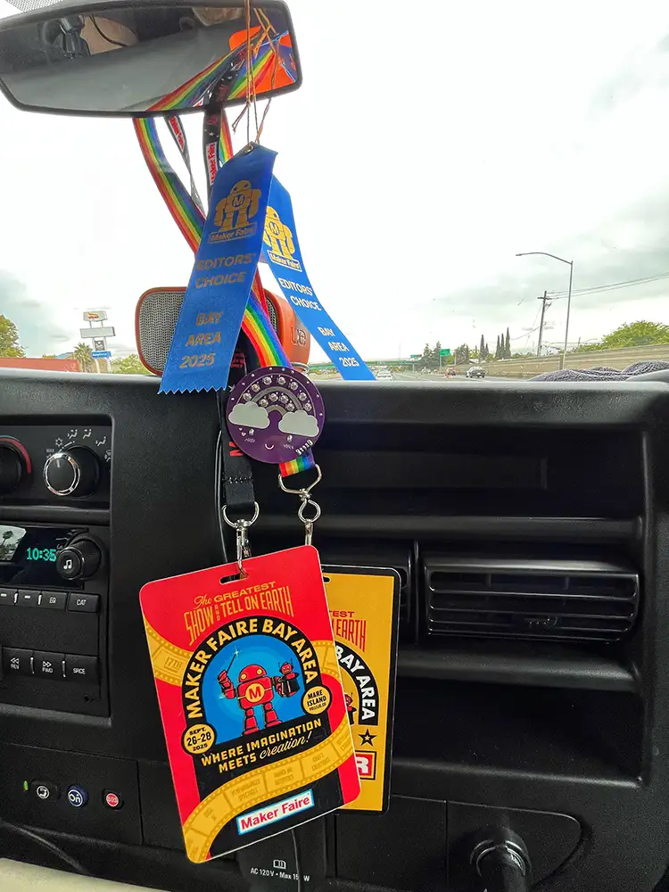 Blue Ribbons and event badges hang from a vehicle rear view mirror