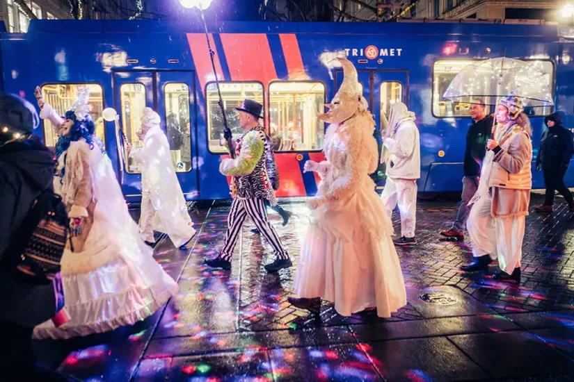 Procession of costumed people at night walking by public transportation train