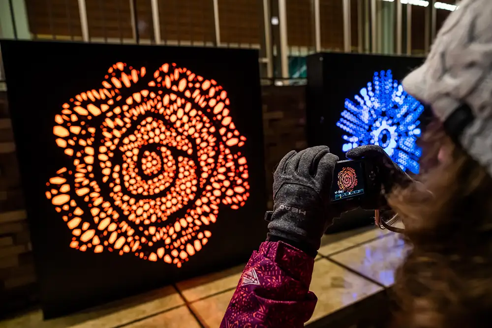 illuminated public art at night as someone takes a cell phone photo