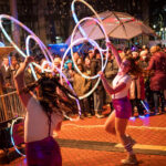 Two woman hula hoop at night to a large audience
